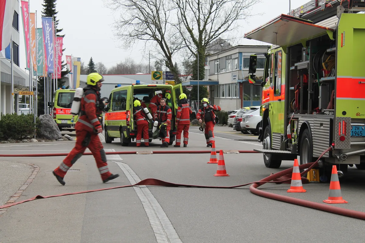 Mehrere Feuerwehrmänner zwischen Einsatzwagen. 